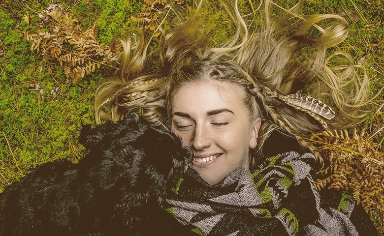 girl laying down on the grass with a dog