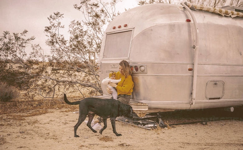 a woman with a baby and a dog near an rv