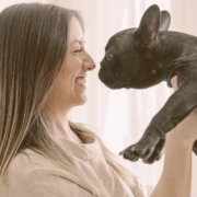 woman smiling holding a French bulldog