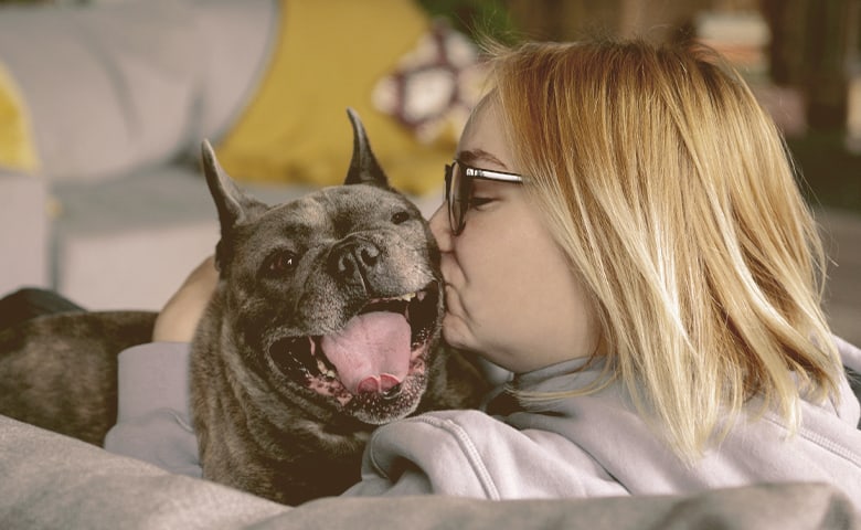 owner giving a kiss to her French bulldog