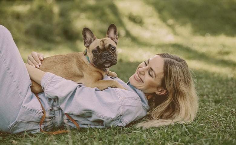 young woman with her french bulldog on the park